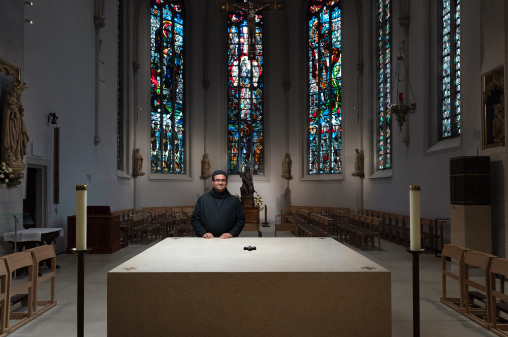 Beneditine Pater Ephrem at St Clement church in Telgte with the wooden statue of the Mother of God in the background.